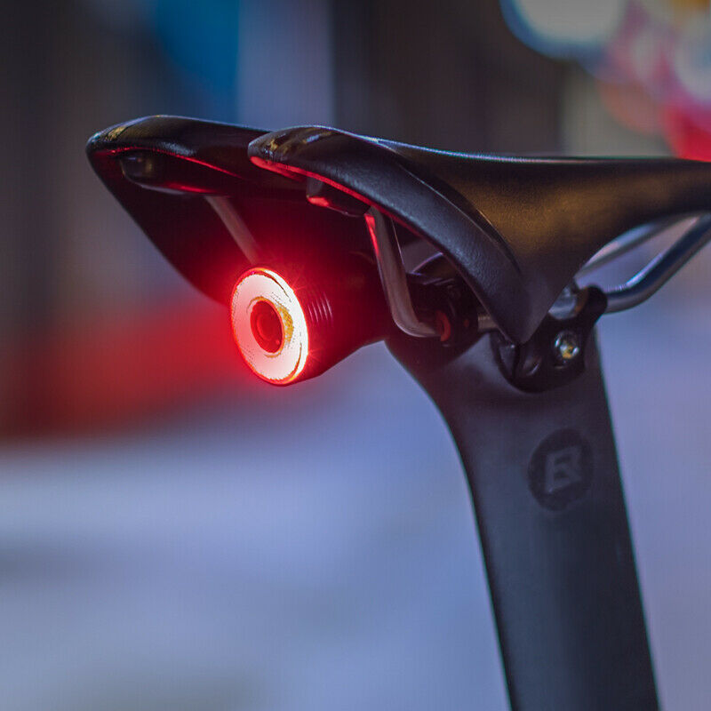 ROCKBROS Smart Brake & Tail Light mounted on bicycle saddle, glowing red for visibility.